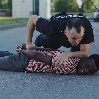 A police officer holding a man on the ground