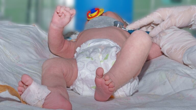 Doctor holding phonendoscope and doing auscultation newborn baby with orthopedic collar