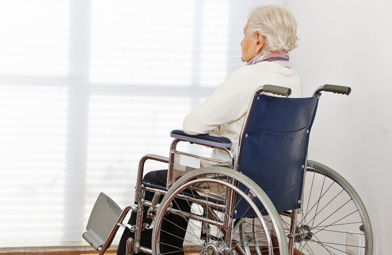 Lonely elderly woman in wheelchair in nursing home