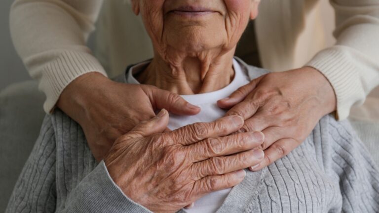 adult daughter hugging her mother from behind holding hands