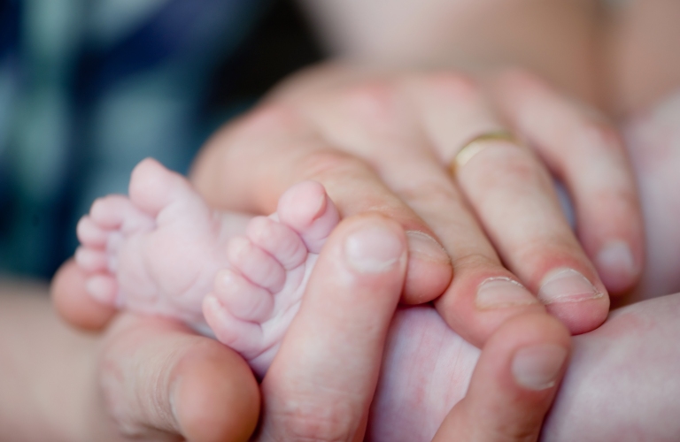 gentle baby feet in father's hands