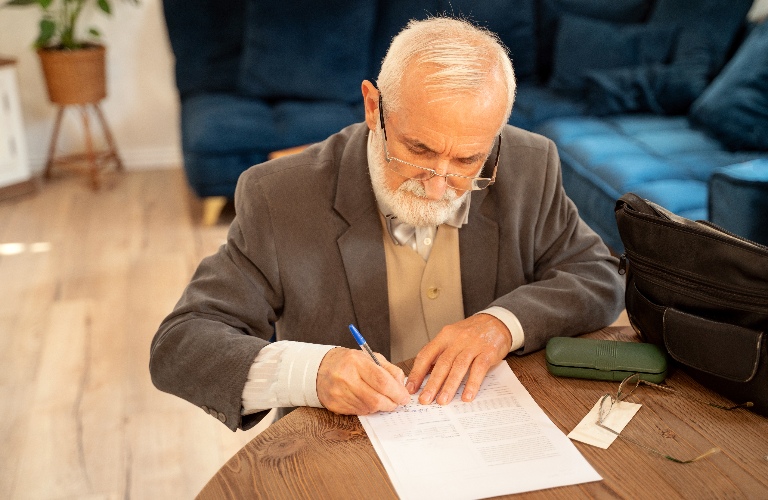 senior man is signing documents