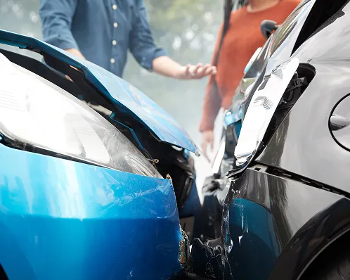 Two cars with front-end collision damage, with two people standing and discussing nearby.
